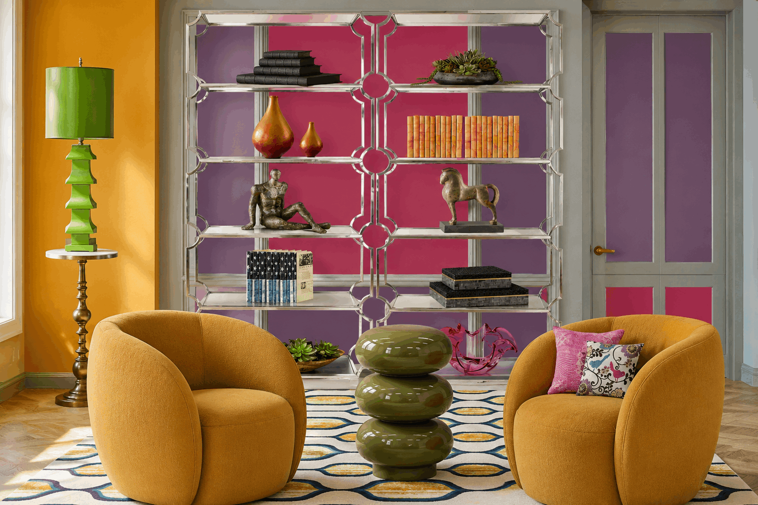 Two bright orange rounded armchairs face a glossy stacked-ceramic table in a colorful living room with a glass geometric bookshelf behind them.
