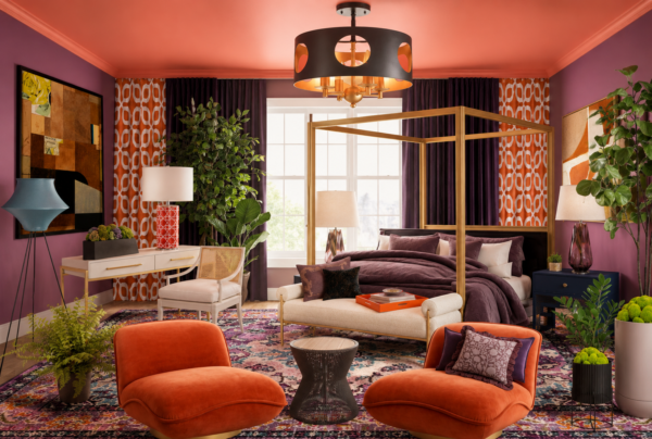 Luxurious burgundy and orange bedroom with a gold four-poster bed, lush plants, and colorful patterned rug.